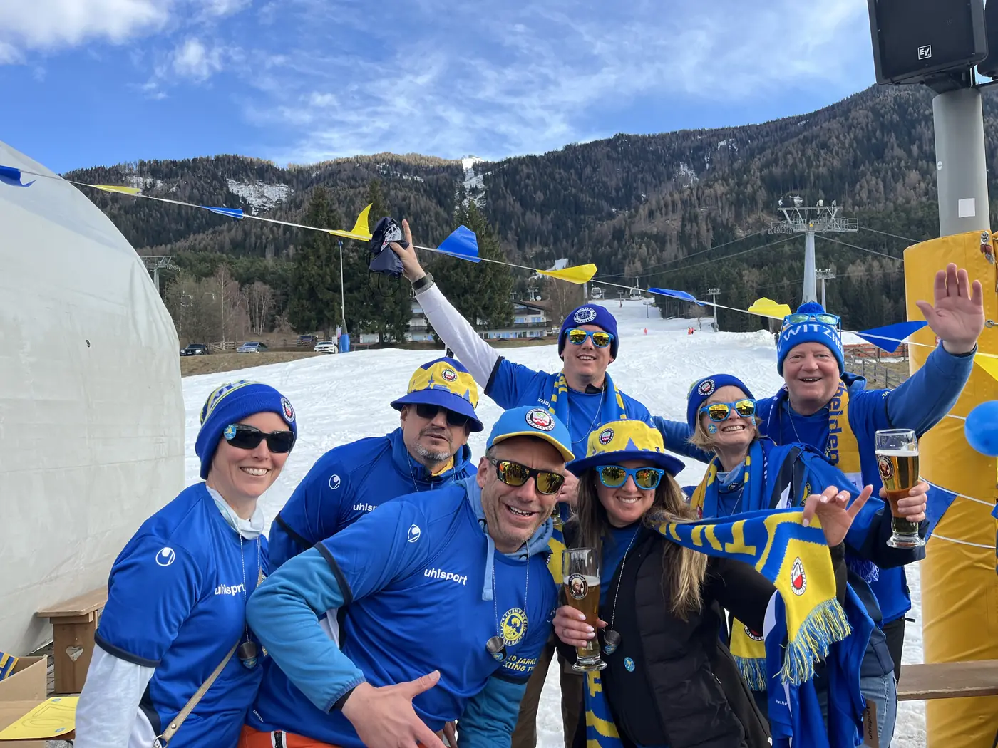 Gruppe in blau-gelben Vereinstrikots stösst an der Talstation an