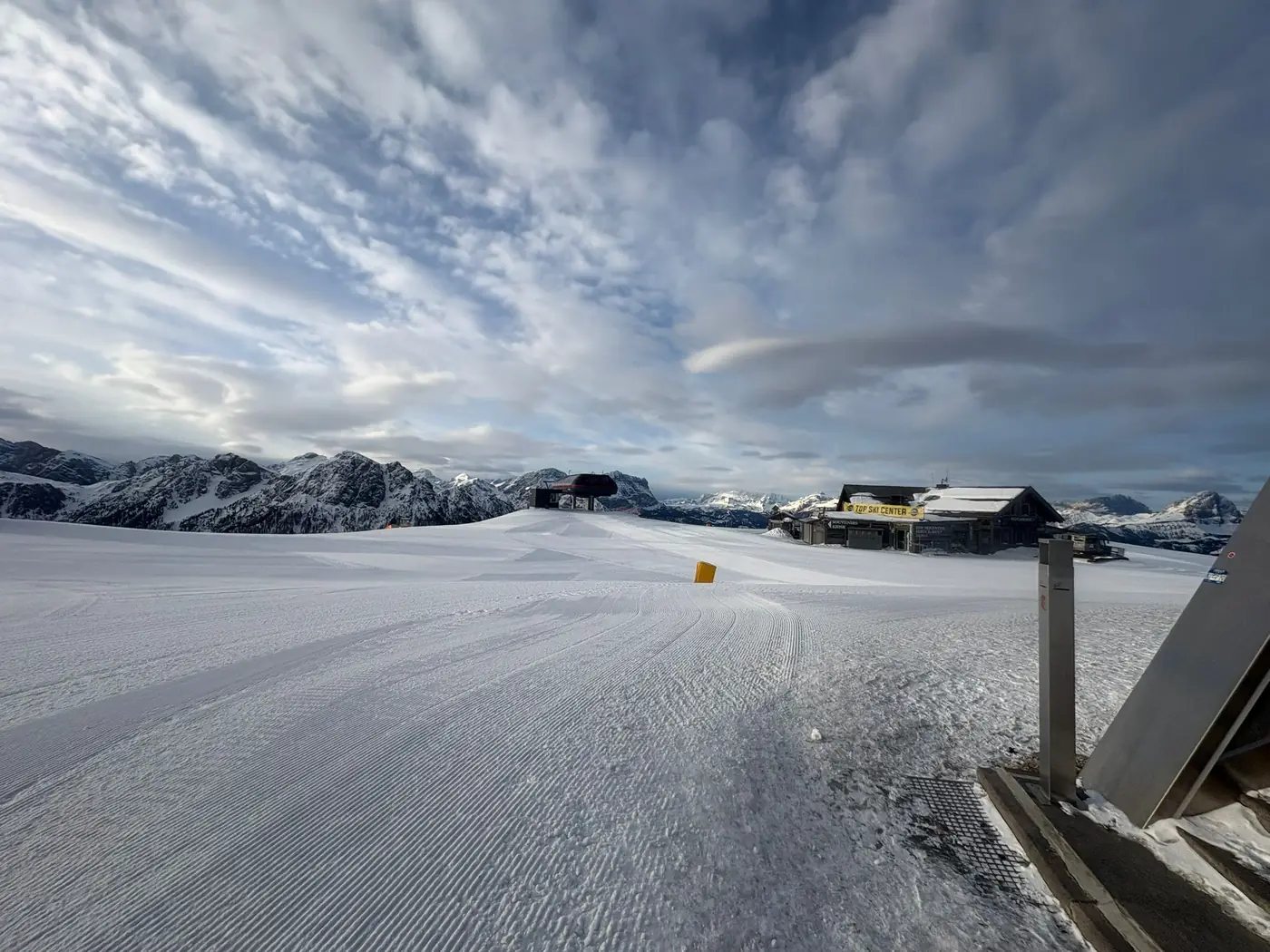 Frisch präparierte, menschenleere Piste mit Dolomiten-Panorama am Morgen