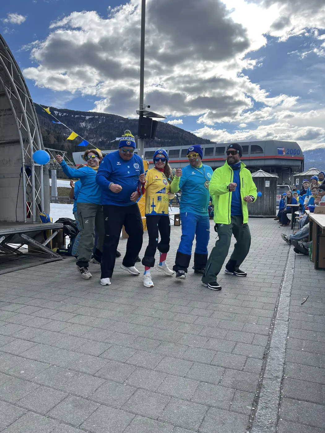 Fünf Personen tanzen ausgelassen auf der Terrasse an der Bergstation
